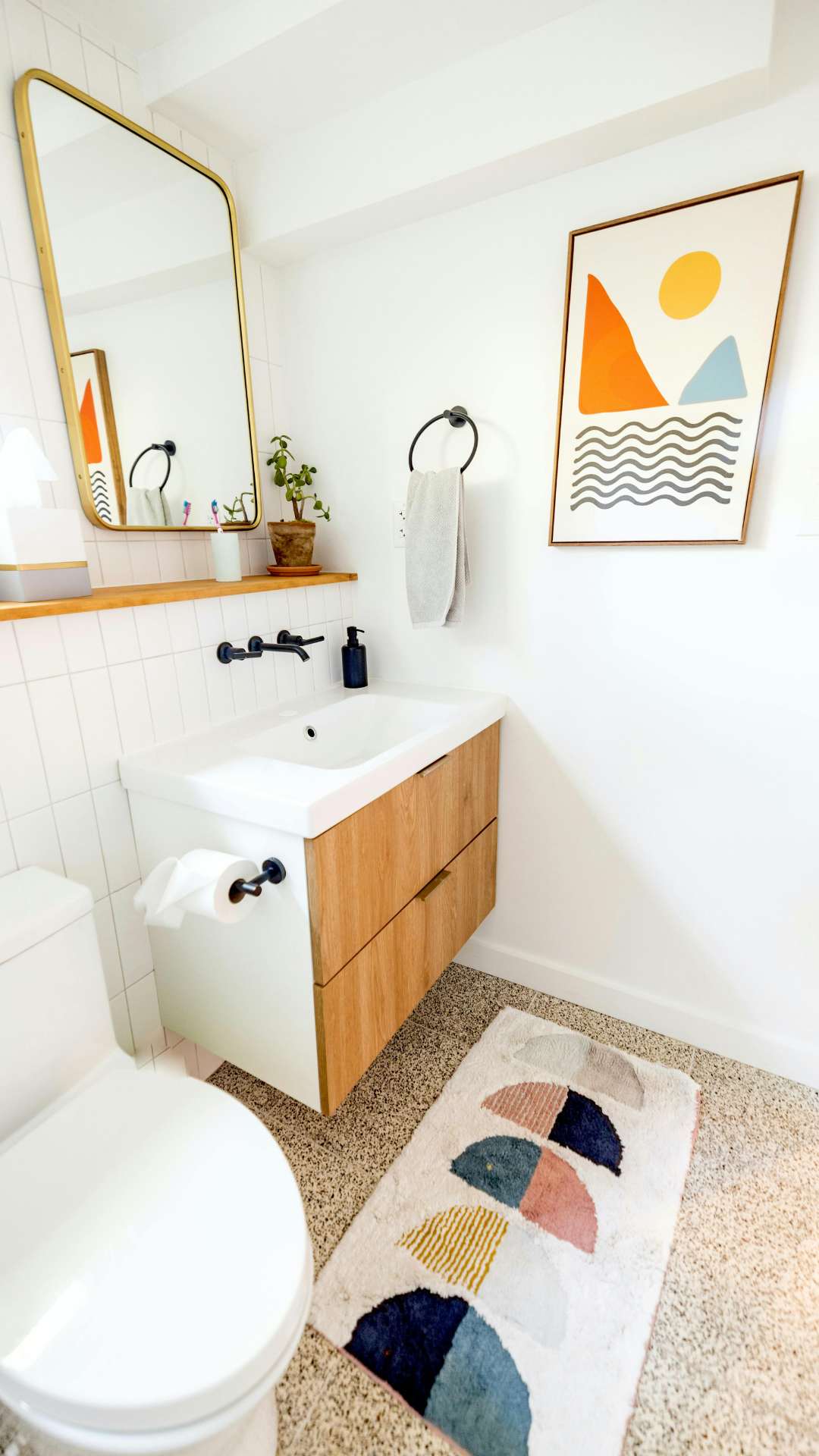 small-bathroom-makeover-featuring-wall-frame-mirror-decorative-rug-and-small-flower-in-a-vase.