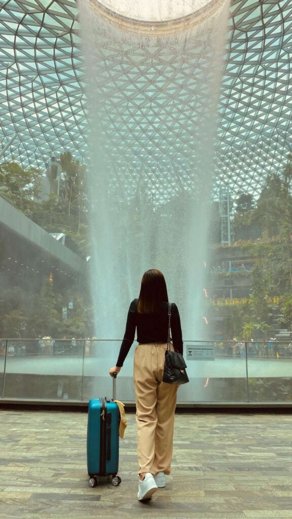A-woman-at-the- airport-wearing-a-chic-comfortable-travel-outfit-soft-knit-top-tailored-trousers-lightweight-coat-and-sneaker-perfectly-capturing- Travel-Outfits-for-Elegance-and-Comfort.