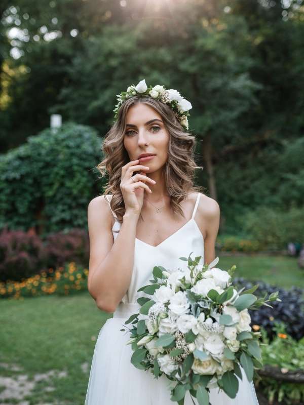Bride-to-be wearing-a-garden-wedding-hair-inspo-hairstyle-with-a-flower-bridal-hairband-perfect-fo-garden-wedding-look. 