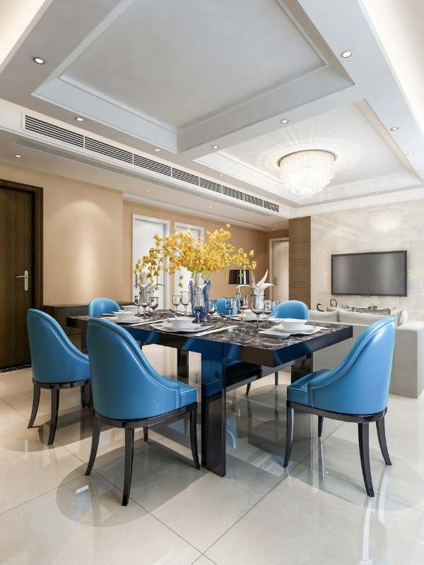 Fine-dining-table-with-a-blue-set-of-chairs-in-the-living-room-styled-with-decorative-accents-soft-lighting-and-a-sophisticated-modern-interior-design-aesthetic. 